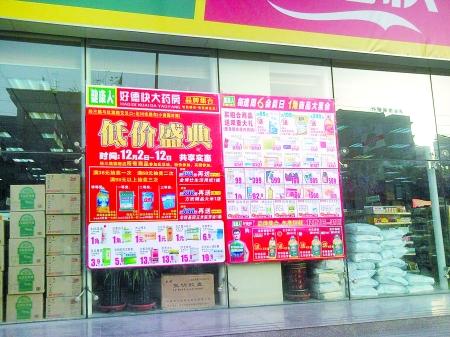 橱窗外摆放着卫生纸,洗洁精,洗衣粉,大米,食用油,电饭锅等礼品,药店的