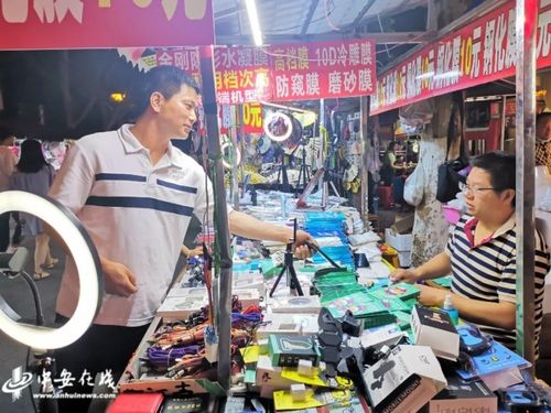 手机贴膜摊主小陶在为市民贴手机膜