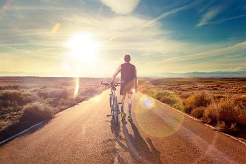 夕阳下推着自行车走的人