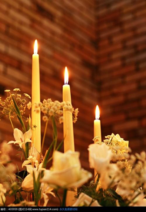 鲜花中的三只点燃的白色蜡烛