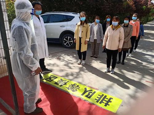 教职工戴口罩在门口间隔一米排队等候.