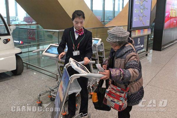 图:机场工作人员向旅客发放智能手推车 摄影:倪嘉云