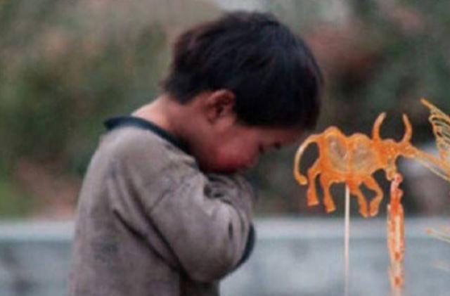 两个衣衫褴褛的小孩子守在画糖人摊位旁,看到孩子的眼神,很心疼