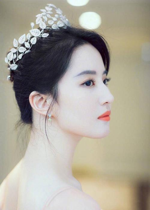 照片中,刘亦菲戴着叶子做的发饰,耳朵上挂着吊坠,妆容精致,青丝茂密