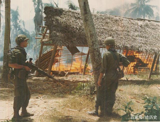 两名越南士兵看着一所可疑的越共房屋倒塌并燃烧.