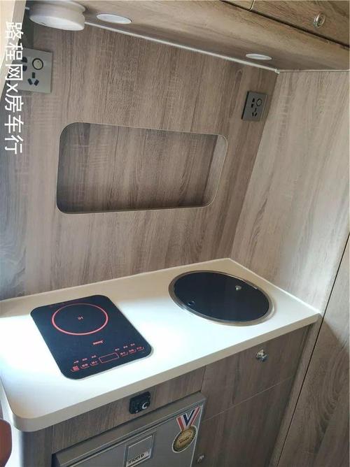 灶台上设有电磁炉和盖板式洗菜盆,电磁炉的上方设有烟雾报警器,储物柜