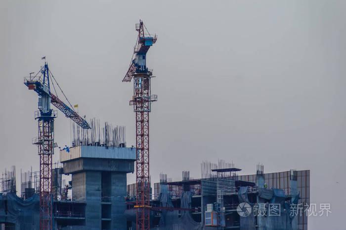 摩天大楼的建设与塔式起重机在顶部的戏剧性的天空背景下.