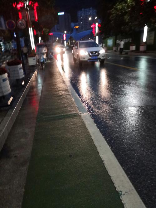 这是马路上的夜景,正在下雨,灯光下明晃晃的,被雨水冲洗的一尘不染.