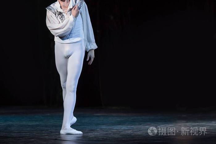 身影男芭蕾舞与黑暗独自在舞台上跳舞的针线活,裤袜和普安特鞋穿衬衫