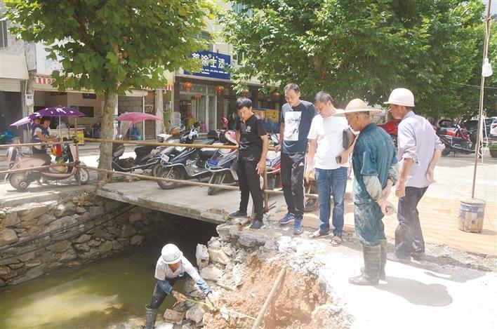 图为黄德夫(右三)在小城镇环境综合整治施工现场监工.