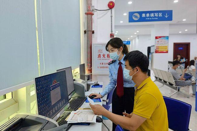 税务人员辅导纳税人通过"广东省电子税务局"办理涉税业务(央广网发
