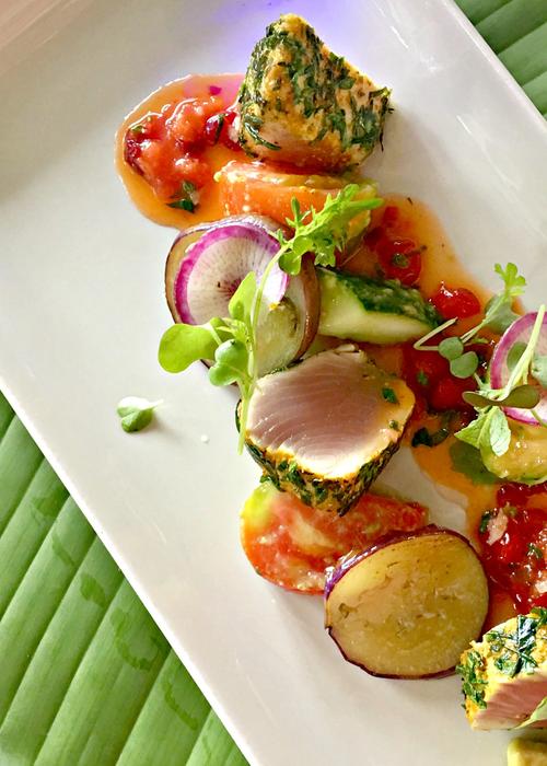 a plate of herb-crusted tuna with fresh vegetables
