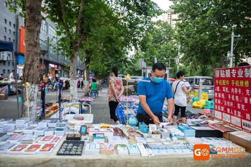靠近廖先生贴膜摊的是个服装摊 摆着各式各样的休闲裤和衣服 摊主是一