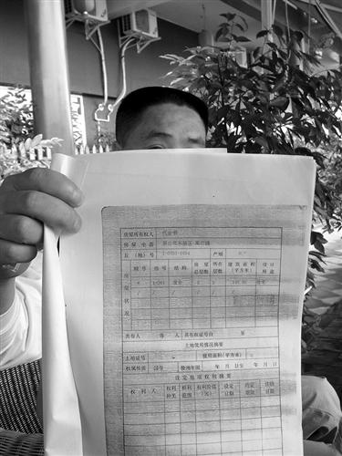 代安书丈夫手持房产证复印件.梁波文图