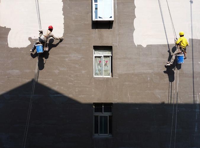 空中画家|||两名外墙粉刷工人,在空中对楼体进行美化粉刷