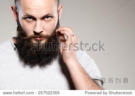 bearded man touching mustache - grey background