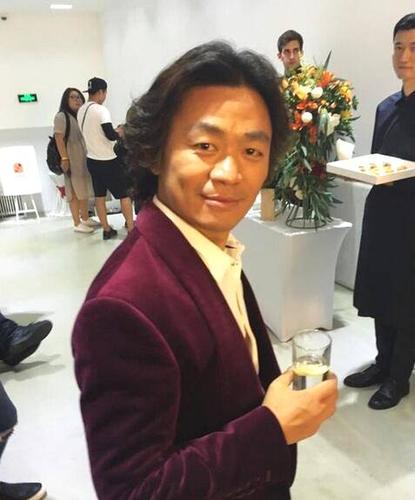 "  照片中,王宝强梳着李咏式的经典长卷发,穿着西装,背影像极了李咏.