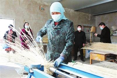 李耀梅正在使用半自动扎扫帚机扎扫帚. 红寺堡宣传部供图