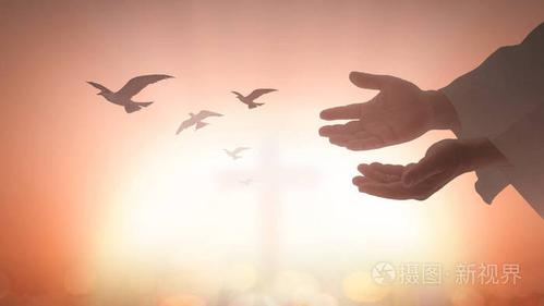 剪羊毛的人张开两只空手,手掌朝上,鸟儿飞过教堂背景的模糊十字架