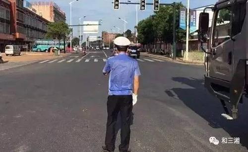 长沙县交警在路口执勤,汗水已经湿透了警服.