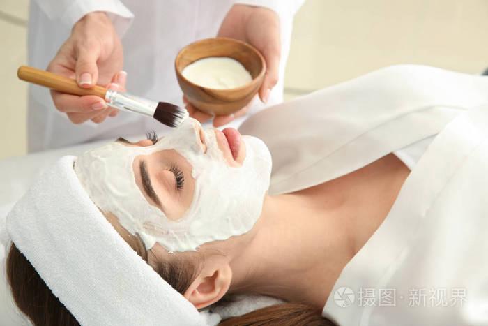 美容师在美容院给年轻女子敷面膜