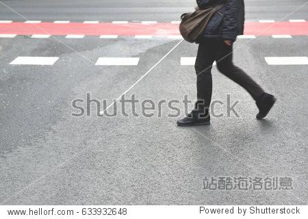 blind person walking with a stick crossing a pedestrian walkway.