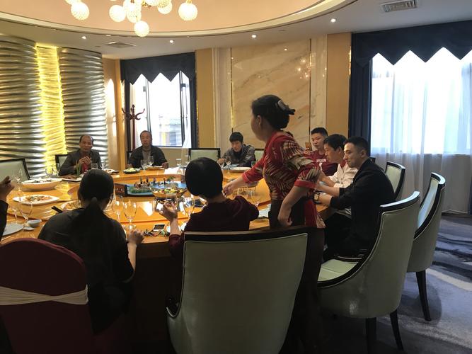 中餐服务员在为生日员工上菜,并介绍菜名.