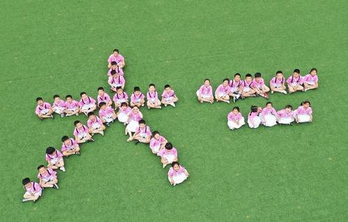 县实验小学附属幼儿园的小朋友在操场上摆出不同的姿势,拍摄毕业照