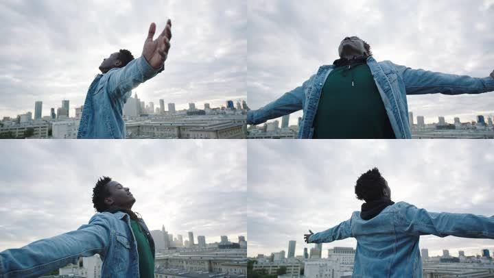 年轻人张开双臂在屋顶上转动.