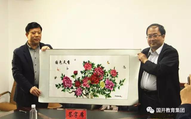 青海化隆县委书记刘建昱(右)向国开教育集团赠送礼物