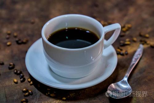 在旧的木制的桌子上放一个白杯黑咖啡