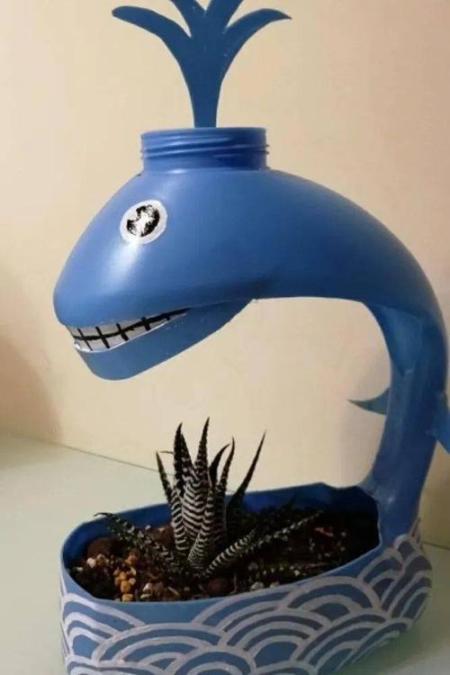 将洗衣液瓶冲洗干净晒干,然后一分为二,在瓶身剪出小海豚造型,同时贴