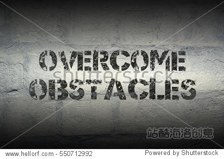 overcome obstacles stencil print on the grunge white brick wall