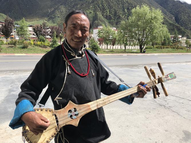 弹扎木聂的藏族艺人,笑容可掬,为游人边弹边唱.