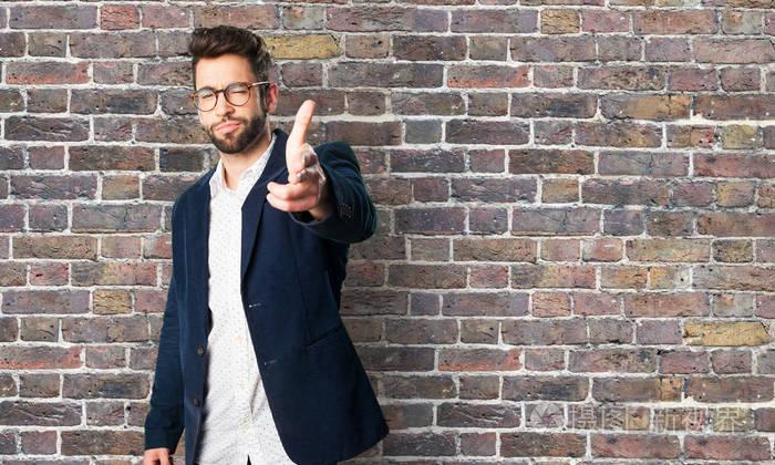 年轻人做枪手势反对砖墙