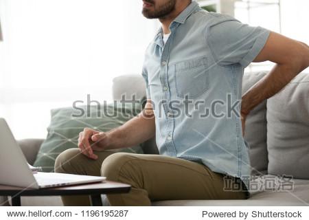 close up millennial man sitting on couch touching