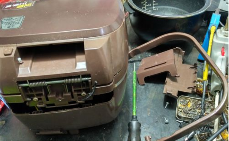 螺丝刀将电饭煲后面的螺丝扭下,取出尾部的盖子即可看见内部的弹簧与