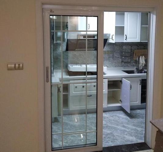 进入厨房,装了白色门框的玻璃推拉门隔开,在客厅就可以直接看到厨房