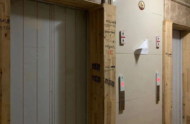电梯门竟然是简陋的木板,木板上写满了广告,也太不豪宅了.