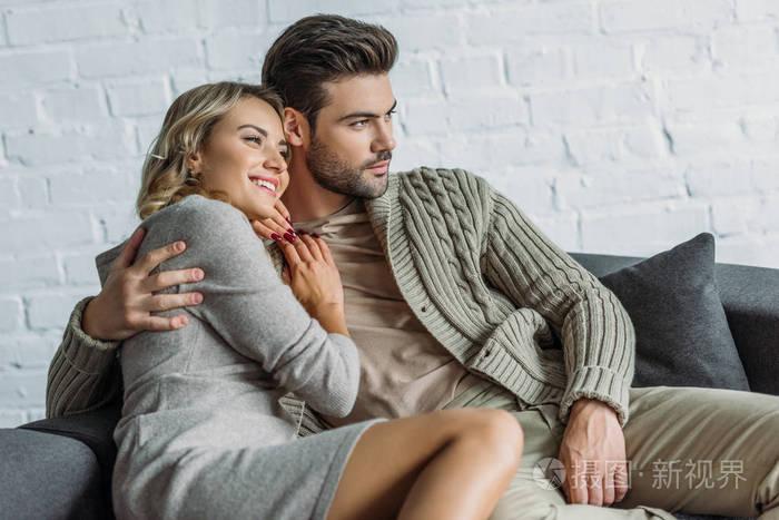 愉快的夫妇拥抱在沙发上客厅和看远