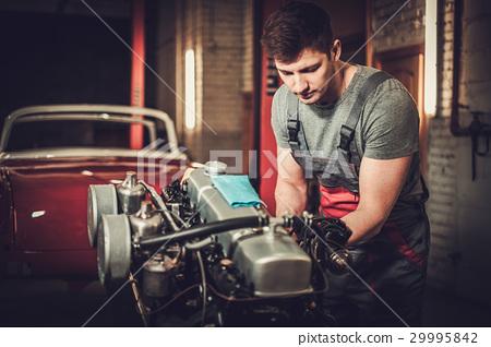照片素材(图片): mechanic working on classic car engine in