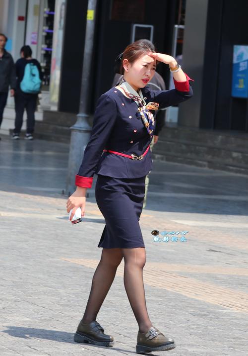 手搭凉棚行走在烈日下的职业装美女