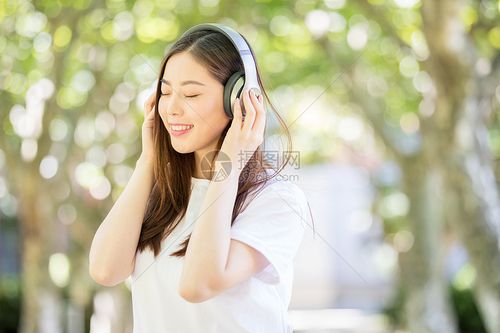 树林下戴耳机听音乐的甜美女生