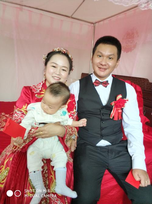 新房里,新娘抱着我的小孙子和新郎合影.