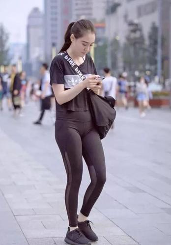 紧身裤小辣妹显凹凸线条低头玩手机成了一道时尚风景线