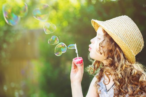 可爱的女孩吹着心形的肥皂泡.