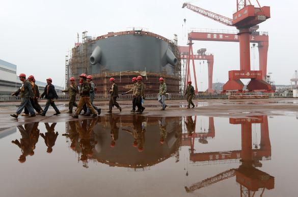图为江苏泰州一家造船厂内的工人从船前经过 中新社