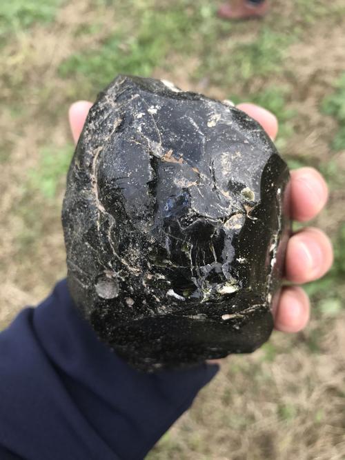 看下这个是不是玻璃陨石?外表黑色,敲碎一点显绿色.