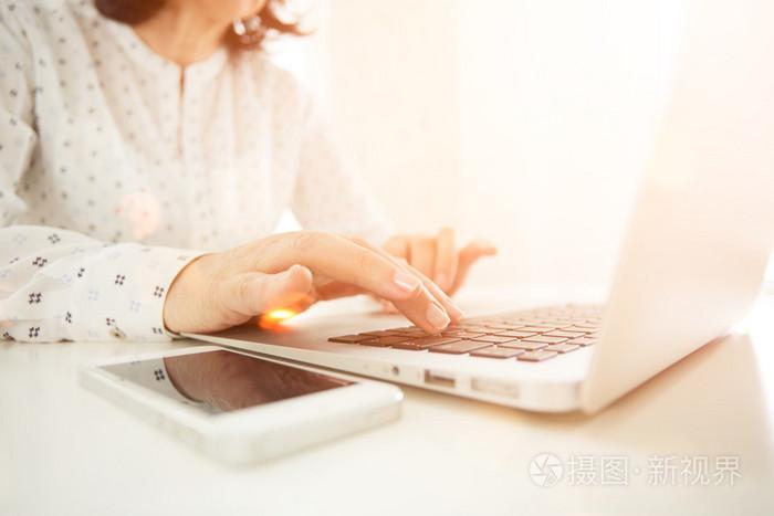 商务女人手忙在办公室的桌前,与 copyspace 使用便携式计算机的后视图